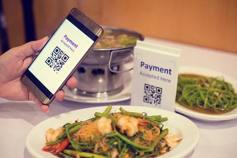 Hand using smart phone to scan QR code on tag with blurry Asian food in resta Stock Photos