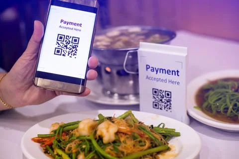 Hand using smart phone to scan QR code on tag with blurry Asian food in resta Stockfoto's