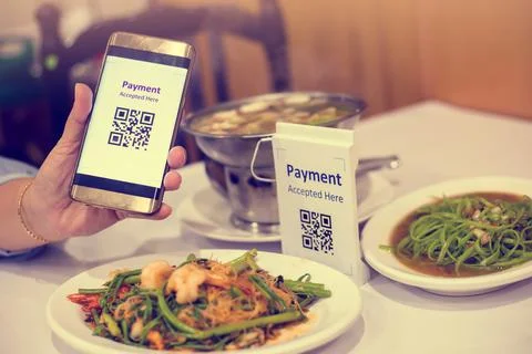 Hand using smart phone to scan QR code on tag with blurry Asian food in resta Stock Photos