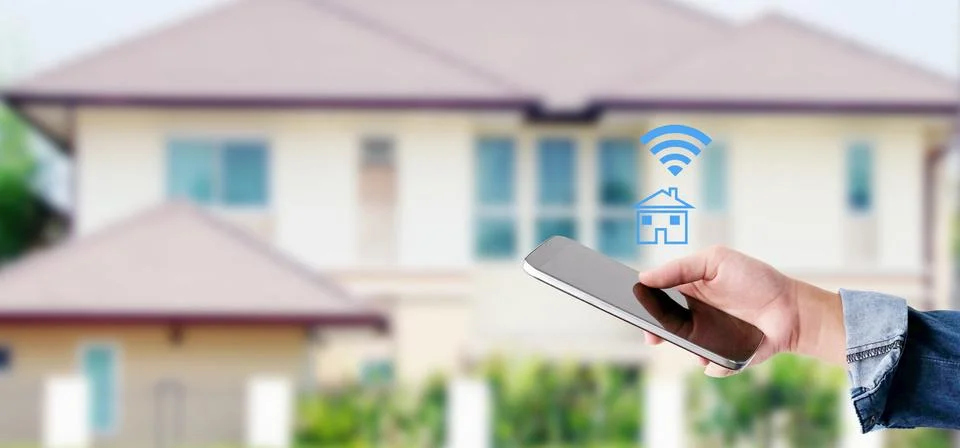 Hand using smart phone with smart home control icon over blur house backgroun Stock Photos