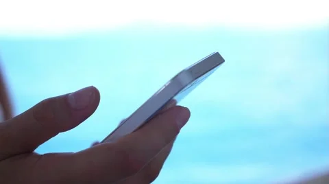 Hand Using Smartphone against the Sea. Slow Motion. Video stock 42220383