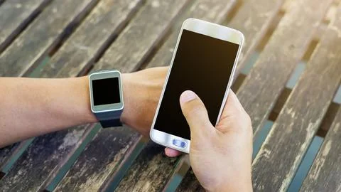 Hand using a smartphone and a smartwatch. Stock Photos