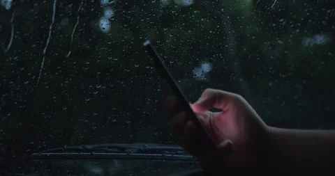 Hand Using Smartphone Behind Rain-Covered Car... Stock Footage 332075306