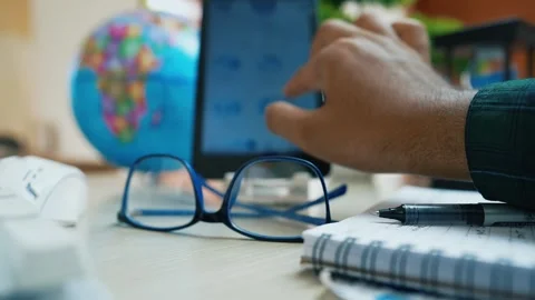Hand Using Smartphone on Desk with Glasses and Globe Stock Footage 318056629