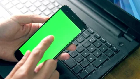 Hand using smartphone with green screen over laptop keyboard Stock-Footage 332282425