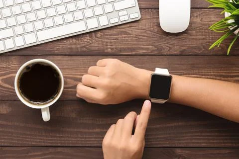 Hand using smartwatch on desk top view Stock Photos