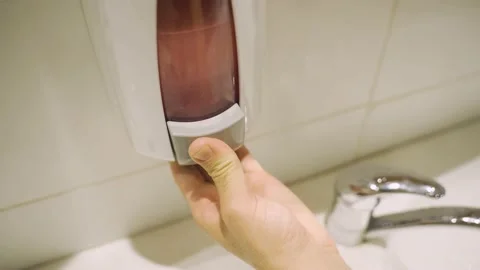 Hand using soap dispenser in public restrooms or toilets then washes in sink Stock Footage 144334921