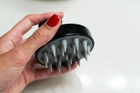 Hand using a soft silicone scalp massage brush Stock Photos
