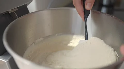 Hand using spatula to mix thick cake batter in metal bowl Stock Footage 317022365