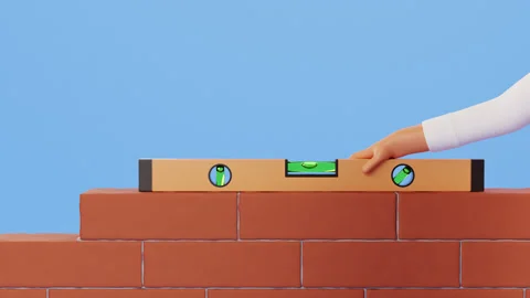 Hand using a spirit level to check the alignment of a brick wall. Stockbeeldmateriaal 300499079