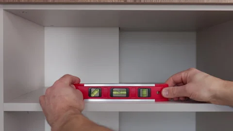 Hand using spirit level to check kitchen cabinet shelf alignment Stock Footage 329935187