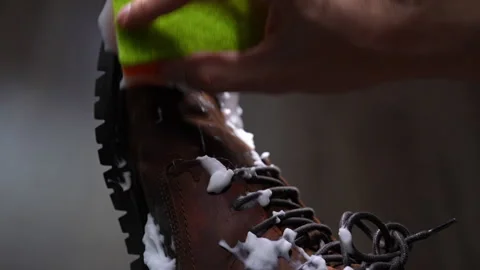 Hand using sponge to wash and clean dirty brown leather boot with soap foam, Stock Footage 342756849