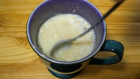 Hand using a spoon to stir a cup of hot mushroom soup. 스톡 동영상 200873083