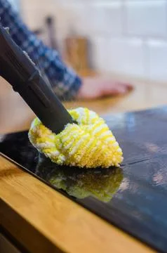 Hand using a steam cleaner with a microfiber cloth to clean a kitchen stovetop. Stock Photos