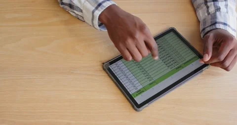 Hand using tablet analyzing data on spreadsheet at office desk Vidéo 345571813