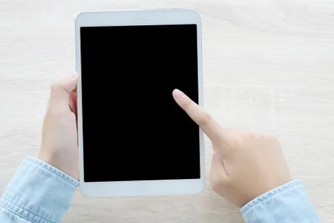 Hand using tablet with blank screen for mock up over table background, busine Stock Photos