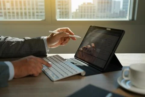Hand using tablet with keyboard displaying financial chart data on desk, re.. 스톡 사진