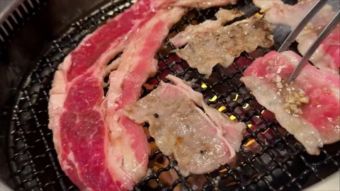 Hand Using Tongs to Grill Beef at Korean Barbecue Restaurant Stock Footage 345915219