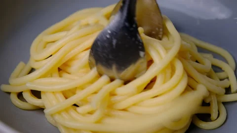 Hand using tongs to pick out the boiled spaghetti and put it on a plate. Stock Footage 179297003