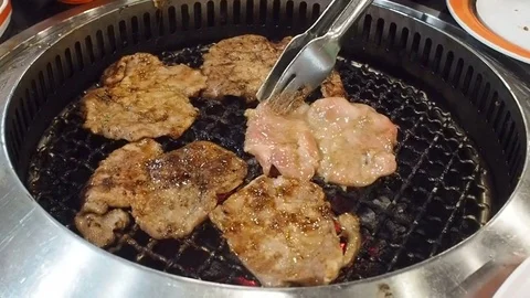 Hand Using Tongs For Turning Meat on the Grill. Grilled pork on the grill. Stock Footage 75812593