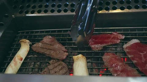 Hand Using Tongs For Turning Meat on the Grill. Grilled meat on the grill. Stock Footage 146822711