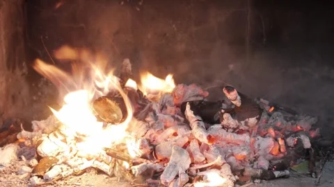 Hand Using Tool to Stir Hot Embers and Ashes in Fireplace, Glowing Coals for Stock Footage 336482564