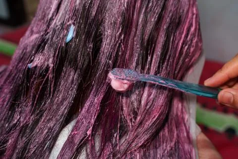 Hand Using Toothbrush to Apply Pink Hair Dye on Dark Hair Stockfoto's