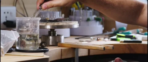 Hand Using Tweezers to Dip a Small Object into a Glass Beaker Vídeo Stock 342562877
