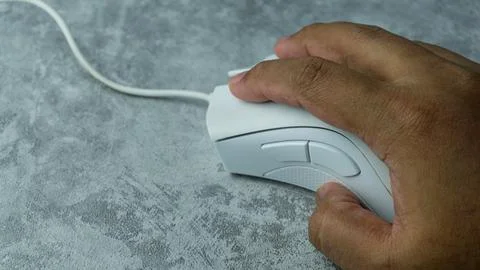 Hand is using a white computer mouse placed on a gray table with a concrete.. Foto stock