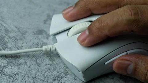 Hand is using a white computer mouse placed on a gray table with a concrete.. Stock Photos