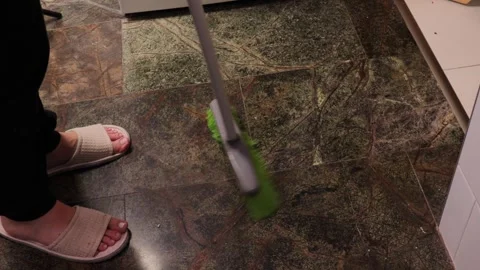 Hand using a wide broom to sweep dust and debris from a tiled floor surface.. Stock Footage 320737986