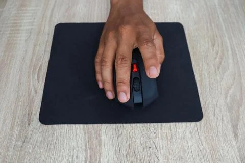 Hand Using A Wireless Computer Mouse On A Wooden Desk Foto stock
