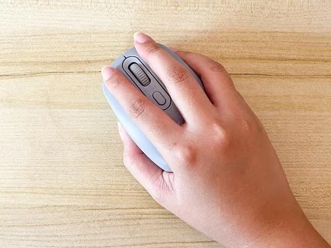 Hand Using Wireless Computer Mouse On Wooden Desk Close-up 库存照片