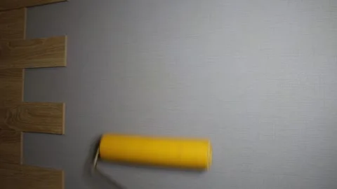 Hand using yellow roller to smooth textured grey wallpaper during home Stock-Footage 329622097