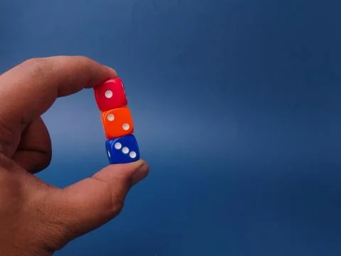 A hand vertically stacks and holds three colorful plastic dicered, orange, .. 写真素材