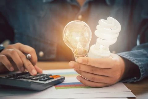 The hand was holding an incandescent light bulb and a spiral light bulb and p Stock Photos