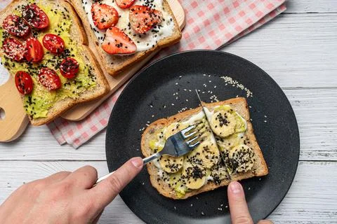 The hand was using a knife and fork to cut the banana Toast. Concept of healt Stock Photos