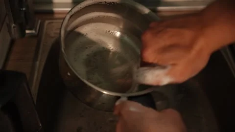 Hand washes metal pot with sponge in kitchen sink Stock Footage 312343969