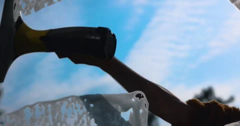 Hand washes window glass with vacuum squeegee cleaner against blue sky Video stock 331802282