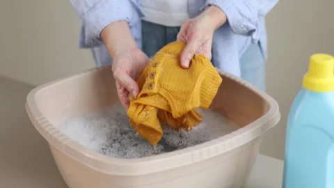 Hand washing children's clothes in soapy water with laundry detergent, gentle Stock Footage 345751735