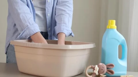 Hand washing children's clothes in soapy water with laundry detergent, gentle Stock Footage 345751763