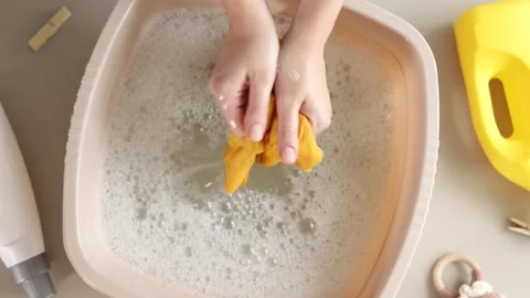 Hand washing children's clothes in soapy water with laundry detergent, gentle Stock Footage 345751820