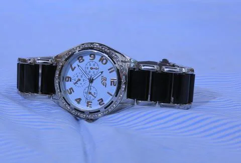 Hand watch on the bed sheets Stock Photos