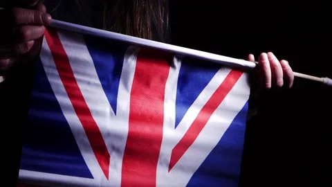 Hand waving British Union Jack flag on dark background Video stock 171937657