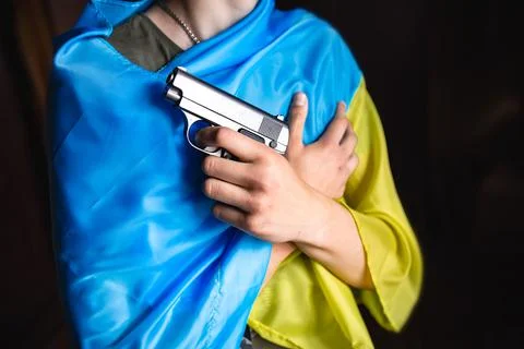 A hand with a weapon on the background of the Ukrainian flag. Bloody hand. Stock Photos