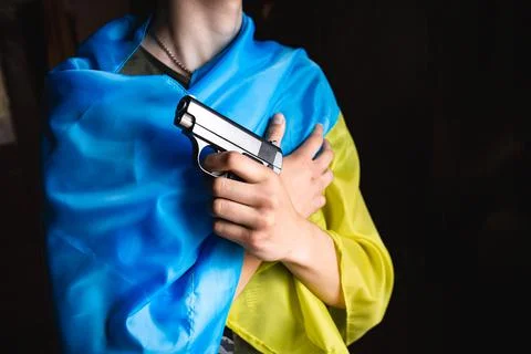 A hand with a weapon on the background of the Ukrainian flag. Bloody hand. Stock Photos