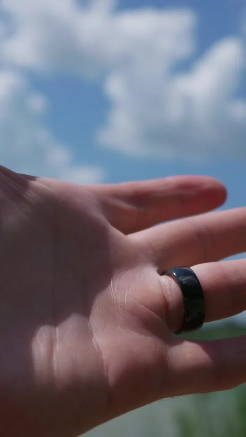 Hand Wearing Black Smart Ring Raised Toward Clouded Blue Sky Stock Footage 341987448