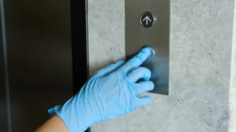 A hand wearing protective rubber gloves is pressing elevator button. Infection 스톡 동영상 131037672