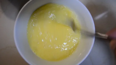 The hand whips with a fork chicken eggs in a bowl in the kitchen to make an omel Stock Footage 118671238
