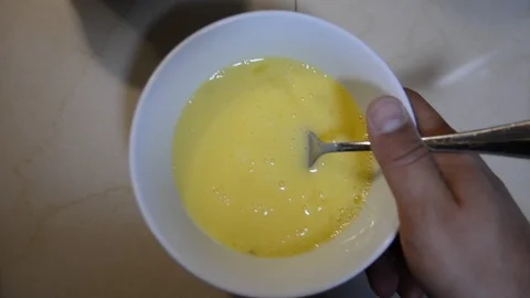 The hand whips with a fork chicken eggs in a bowl in the kitchen to make an omel Видео 118671361